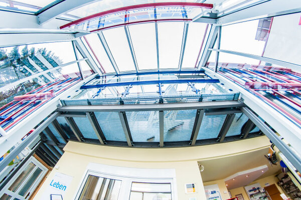 Modernes Glasdach mit Metallkonstruktion und lichtdurchflutetem Eingangsbereich.