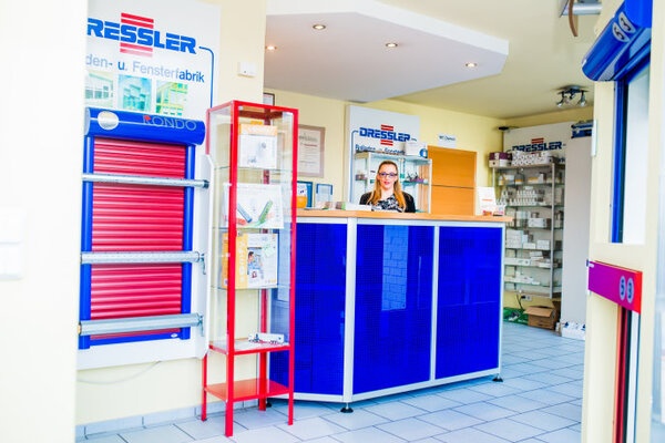 Heller Empfangsbereich einer Rollladen- und Fensterfirma mit moderner blauer Theke.